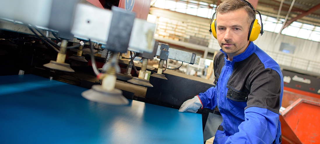 Employee wearing earmuff PPE to protect against hearing loss.