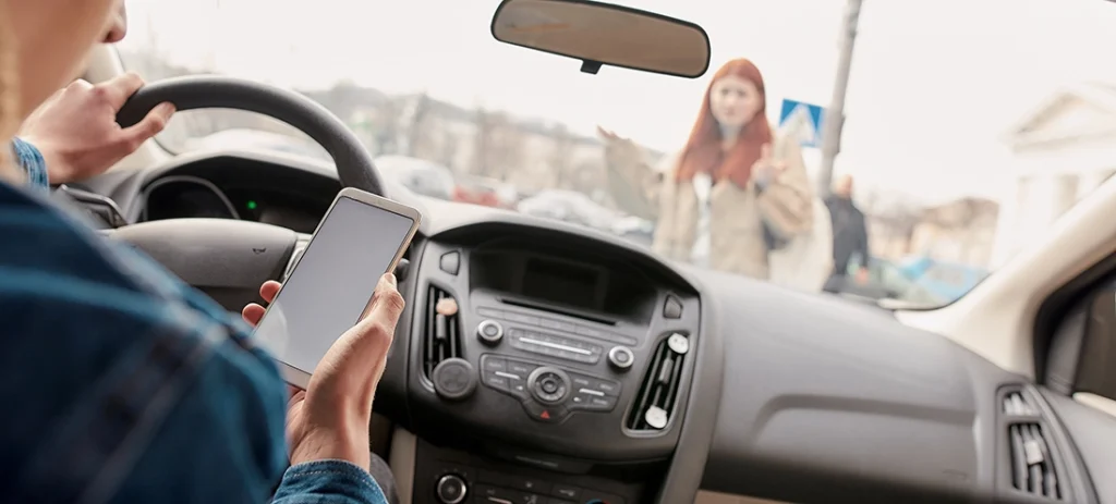 A person uses their mobile phone while driving.