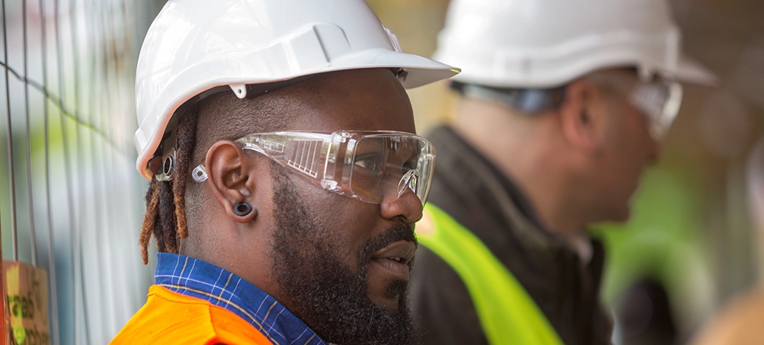 Two men wearing protective eye equipment and hardhats.