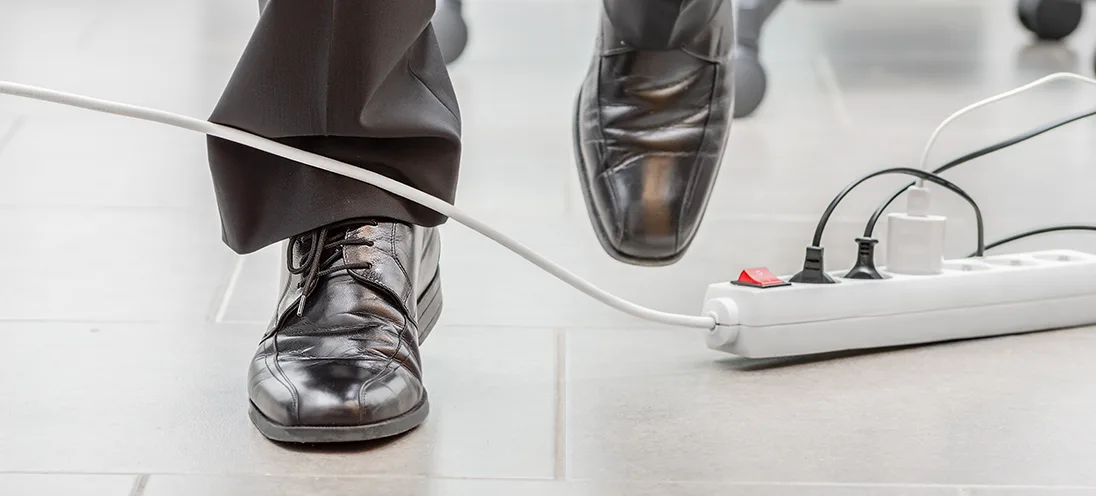 Person tripping over an electrical cord connected to a power strip.