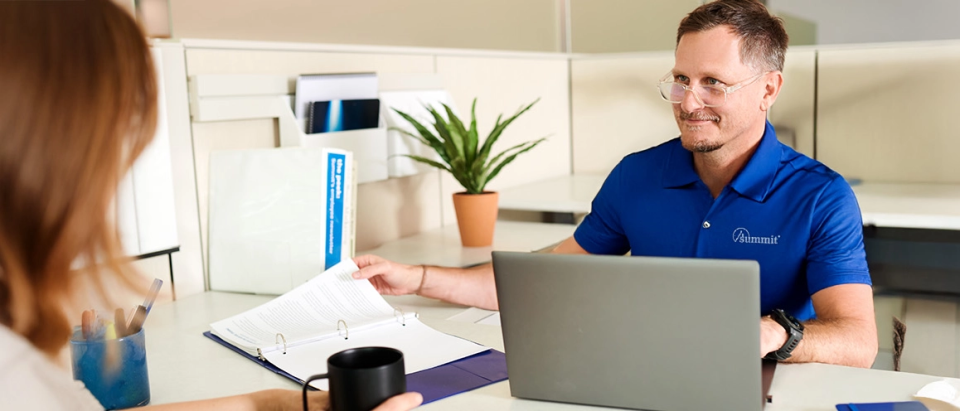 Summit premium auditor sitting at a desk helping client with an audit .