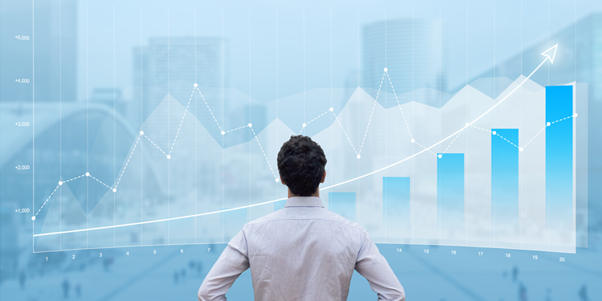 Man in dress shirt looks up at a graph projecting financial growth.