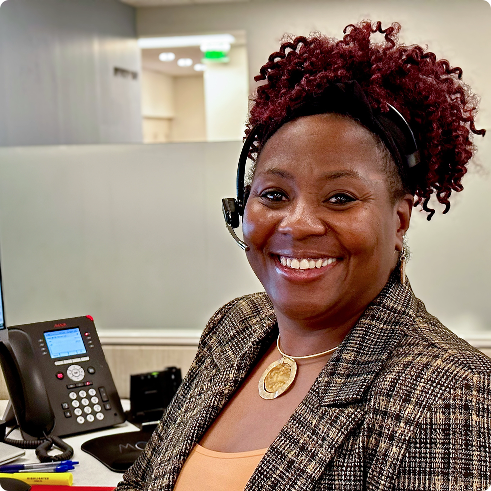 Summit employee wearing a headset and sitting at her desk smiling.