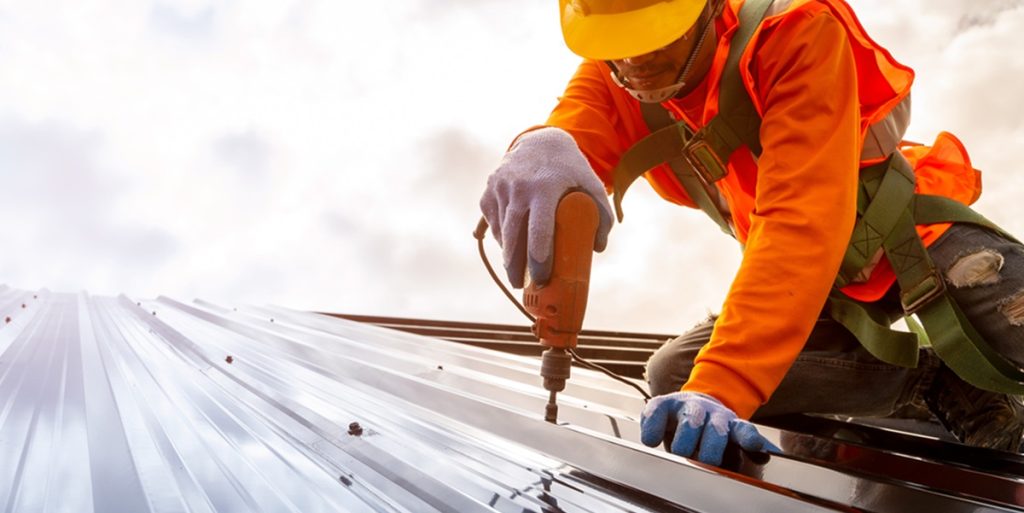 Roofer using power tools on a metal roof.