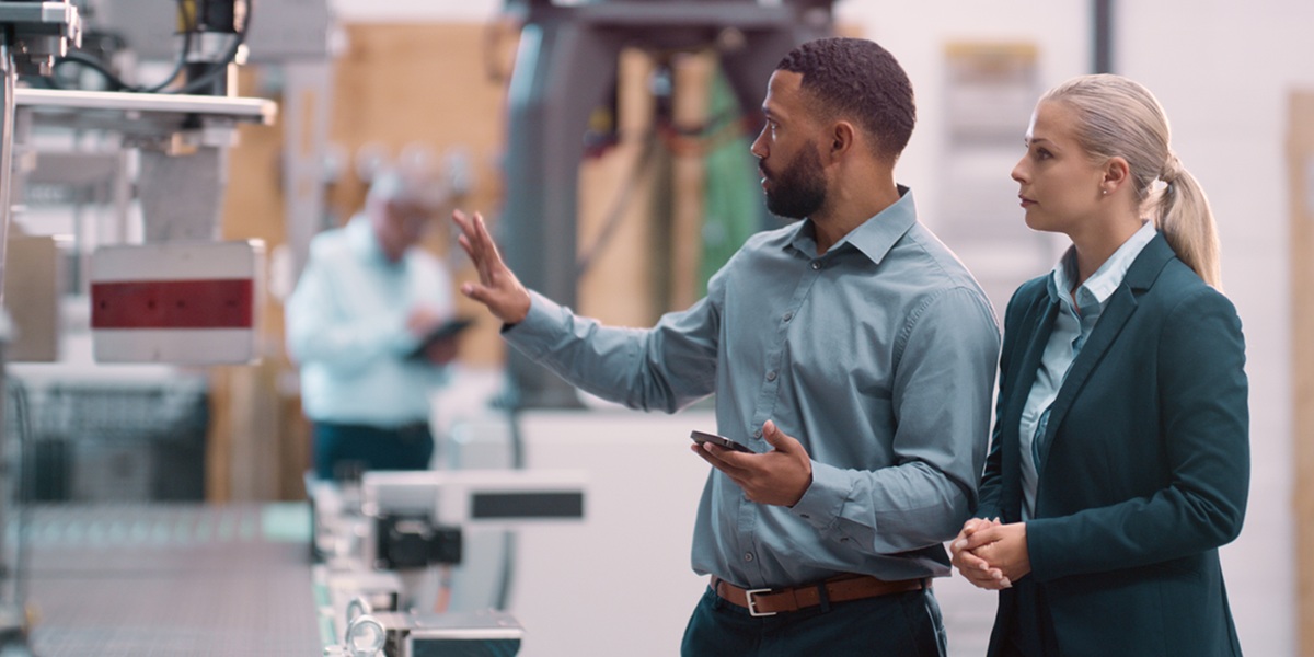 Two people in business clothing examine equipment from afar.